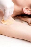 Cosmetologist applying wax paste on armpit photo