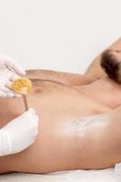 Cosmetologist applying wax paste on armpit photo