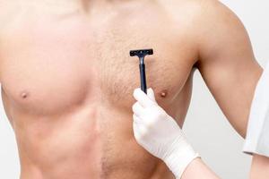 Beautician shaves chest of young man photo