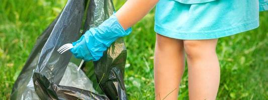 Child picks plastic trash from grass photo