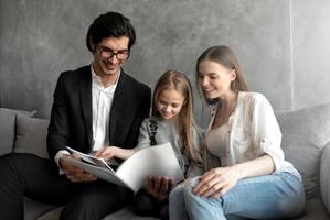 Happy little girl reads a book with her parents photo