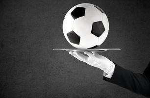Waiter that holds a tray with soccer ball. Concept of first class service on soccer photo