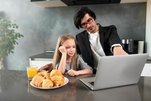 contento pequeño niña acecho un película en el computadora con su padre foto