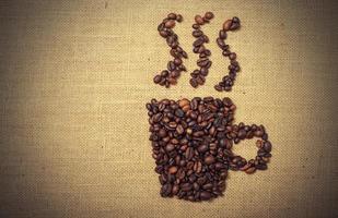 Coffee beans shaped as cup over a jute cloth photo