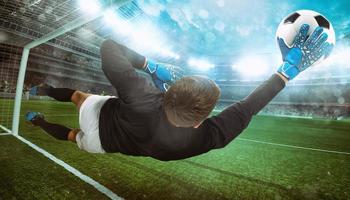 Goalkeeper catches the ball in the stadium during a football game photo