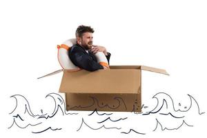 Afraid businessman with cardboard in the ocean photo