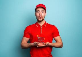 Deliveryman shows the cart where to buy. Cyan background photo