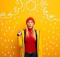 Girl indicates the sun between the clouds above. Amazed and shocked expression. Yellow background photo