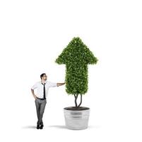 Businessman that cultivates a plant with a shape of arrow. Concept of growing of company economy . photo