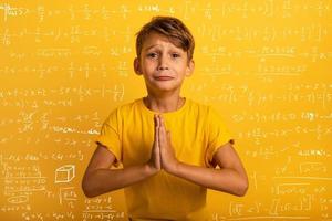 Child is pleading because he does not want to study. Yellow background photo