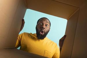 Happy boy receives a package from online shop order. happy and surprised expression. Blue background. photo