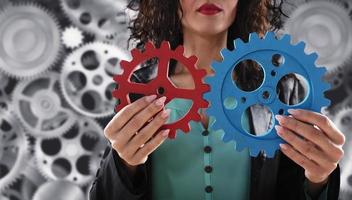 mujer de negocios intentos a conectar engranajes piezas. concepto de trabajo en equipo, camaradería y integración. foto