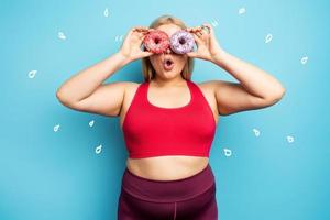 Fat girl thinks to eat donuts instead of does gym. Concept of indecision and doubt photo