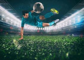 Soccer striker hits the ball with an acrobatic kick in the air at the stadium photo