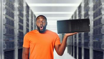 Surprised black man holds a server in hand. Concept of hosting and storage photo