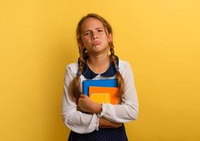 Girl cries because he has a lot of school homework. Emotional expression. Yellow background photo