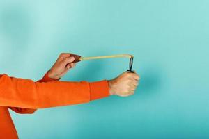 Man ready to throw from the slingshot something. cyan background photo