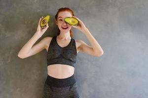 atlético niña con gimnasio ropa come aguacate a hogar foto