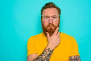 Man with yellow t-shirt and beard is very undecided photo