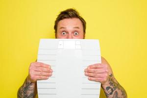 Amazed man with beard and tattoos is hidden behind the scales photo