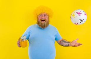 Fat happy happy man with wig in head and sunglasses drinks a fruit juice photo