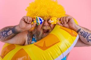 Fat happy man with wig in head is ready to swim with a donut lifesaver photo