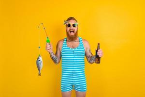 man with beard and swimsuit caught a fish photo