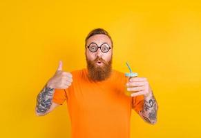 Nerd happy man with glasses drinks a fruit juice photo