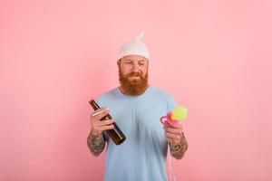 Thoughtful man with beard and tattoos acts like a little newborn baby with beer in hand photo