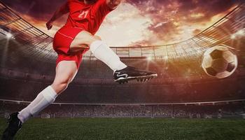 Close up of a soccer scene during a match with player in a red uniform kicking the ball with power photo