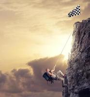 Businessman climb a mountain to get the flag. Achievement business goal and difficult career concept photo