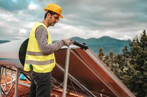 Man works on renewable energy system with solar panel for hot water photo