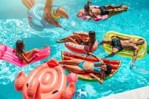 amigos en traje de baño en el piscina consiguiendo un bronceado foto