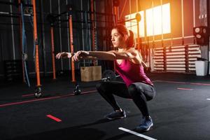 Athletic girl does squat exercises at the gym photo