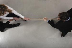 Rival business man and woman compete for the command by pulling the rope photo