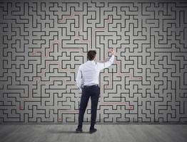 Businessman draws the solution of a labyrinth. Concept of problem solving photo