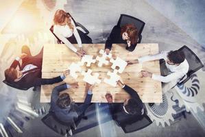Teamwork of partners. Concept of integration and startup with puzzle pieces and gear overlay. double exposure photo