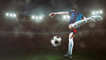 Football scene at night match with player kicking the ball with power photo