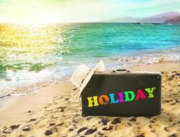 Suitcase in a tropical beach with holiday writing photo