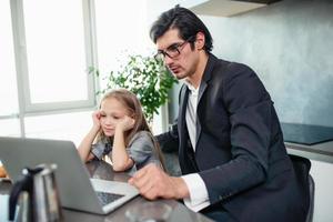 contento pequeño niña acecho un película en el computadora con su padre foto