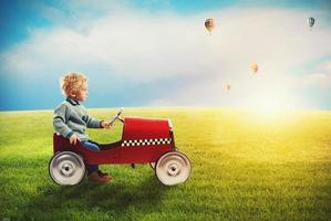 Child with car plays in a green field photo