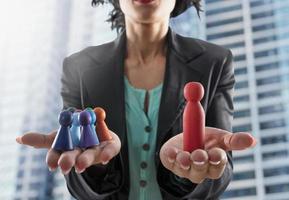 Business woman holds wooden toy shaped as person. Concept of business teamwork and leadership photo