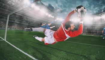 Goalkeeper catches the ball in the stadium during a football game photo