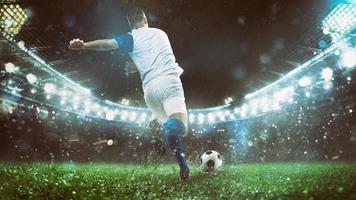 cerca arriba de un fútbol escena a noche partido con jugador en un blanco y azul uniforme pateando el pelota con poder foto