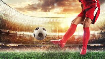fútbol escena a el estadio con jugador en un rojo uniforme pateando el pelota foto