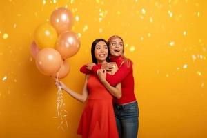 Girls ready for a party with balloons. Joyful an happiness expression. Yellow background photo