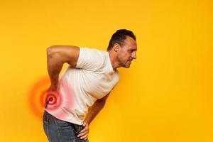 Aching man with back pain. Yellow background photo