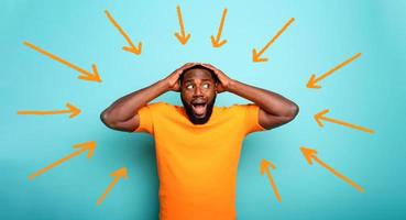 Feared, confused and shocked expression of a boy followed by arrows. cyan colored background photo