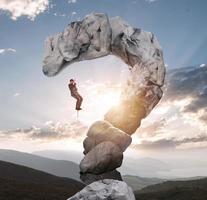 Businessman tries to climb with difficulty on a mountain shaped as question mark photo