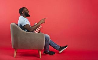Man has fun watching a film. Concept of entertainment and streaming tv. red background photo